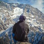 A lone trekker gazes across the snowy mountains of Dharamshala, India.
